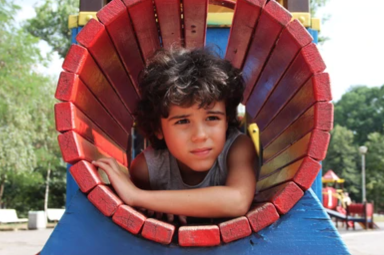 Child laying down inside of a playground tunnel